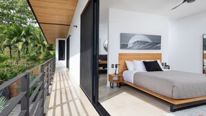 Une chambre moderne avec un grand lit, un ventilateur de plafond et une vue sur une végétation luxuriante.