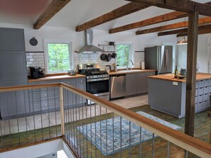 Eine moderne Küche mit einer zentralen Kochinsel, Edelstahlgeräten und einer Holzbalkendecke.