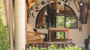 A cozy porch with a wicker chair, a small wooden table, and a large arched window overlooking greenery. - Wonderful private villa for 2 guests with TV, patio and pets allowed (Belmonte)