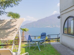 Une terrasse avec une table et des chaises donnant sur un lac et des montagnes.