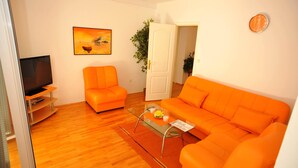 A living room with two orange sofas, a glass coffee table, a flat-screen TV, and a painting on the wall. - Villa Anni - Two-Bedroom Apartment with Terrace (Sutivan)