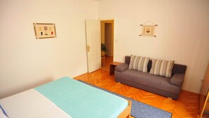A room with a bed, a sofa, a wooden floor, and a door leading to another room. - Villa Anni-Two Bedroom Apartment with Sea View Terrace (Sutivan)