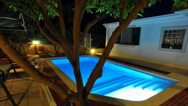A swimming pool with a tree in the foreground, a white building with windows, and outdoor furniture. - Villa Anni-Two Bedroom Apartment with Sea View Terrace (Sutivan)