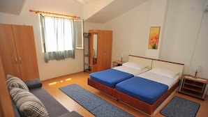 Ein Schlafzimmer mit zwei Betten, einem Kleiderschrank, einem Sofa und einem Fenster mit Vorhängen.