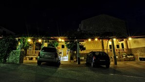 Ein Gebäude mit steinverkleideter Fassade, einem ehrfurchtgebietenden Eingang und zwei geparkten Autos.