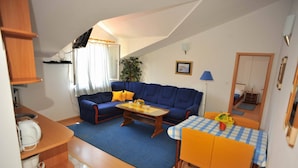Ein gemütlicher Wohnraum mit Sofa, Couchtisch und Esstisch mit Stühlen.