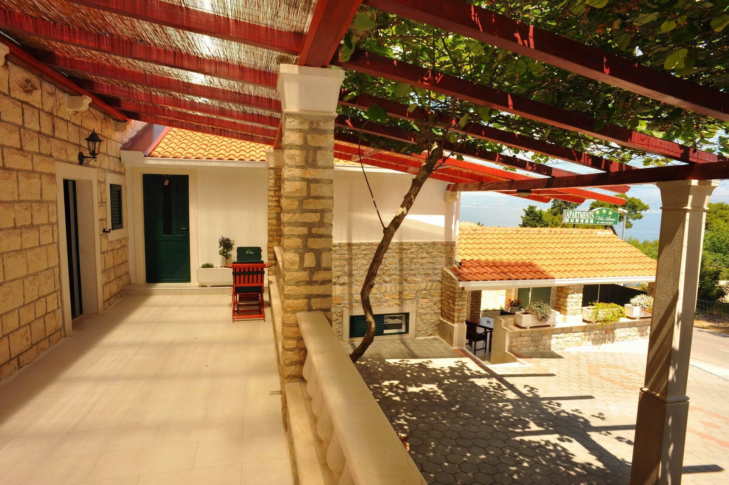 Uma área externa coberta com parede de pedra, porta verde e um banco vermelho.