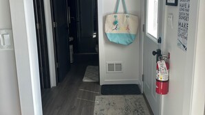 Un couloir avec un extincteur, un sac accroché à un crochet et une affiche sur le mur.