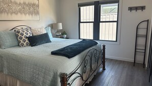 Une chambre à coucher avec un lit, une fenêtre, une table de chevet, une lampe et une échelle.