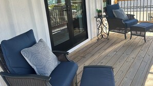 Un espace extérieur aménagé, abrité et doté de meubles en osier, ainsi que d’une porte-fenêtre coulissante.