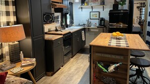 A modern kitchen with black appliances, wooden countertops, and a central island with a checkered tablecloth. - Coco's Cabin #3, Where pets stay free (Goodlettsville)