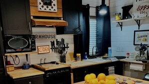 A kitchen with a wooden table, a microwave, and a sign that says "KITCHEN". - Coco's Cabin #3, Where pets stay free (Goodlettsville)