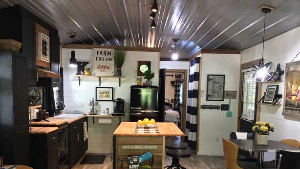 A cozy kitchen with a wooden table, a refrigerator, and a coffee machine. There is a sign that says "Farm Fresh Eggs" and a "Coffee" sign. - Coco's Cabin #3, Where pets stay free (Goodlettsville)