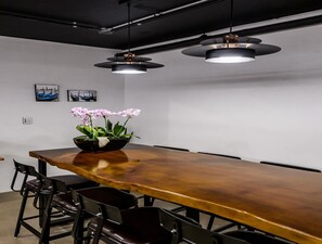 A conference room with a long wooden table, black chairs, and two pendant lights. - Hotel HYGGELIG - Hostel (Busan)