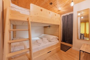 Ein Mehrbettzimmer mit Holzlade, Spiegel und kleinem Tisch.