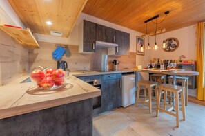 Eine moderne Küche mit Holzausstattung, einem eingebauten Ofen und einem Essbereich mit Hockstühlen.