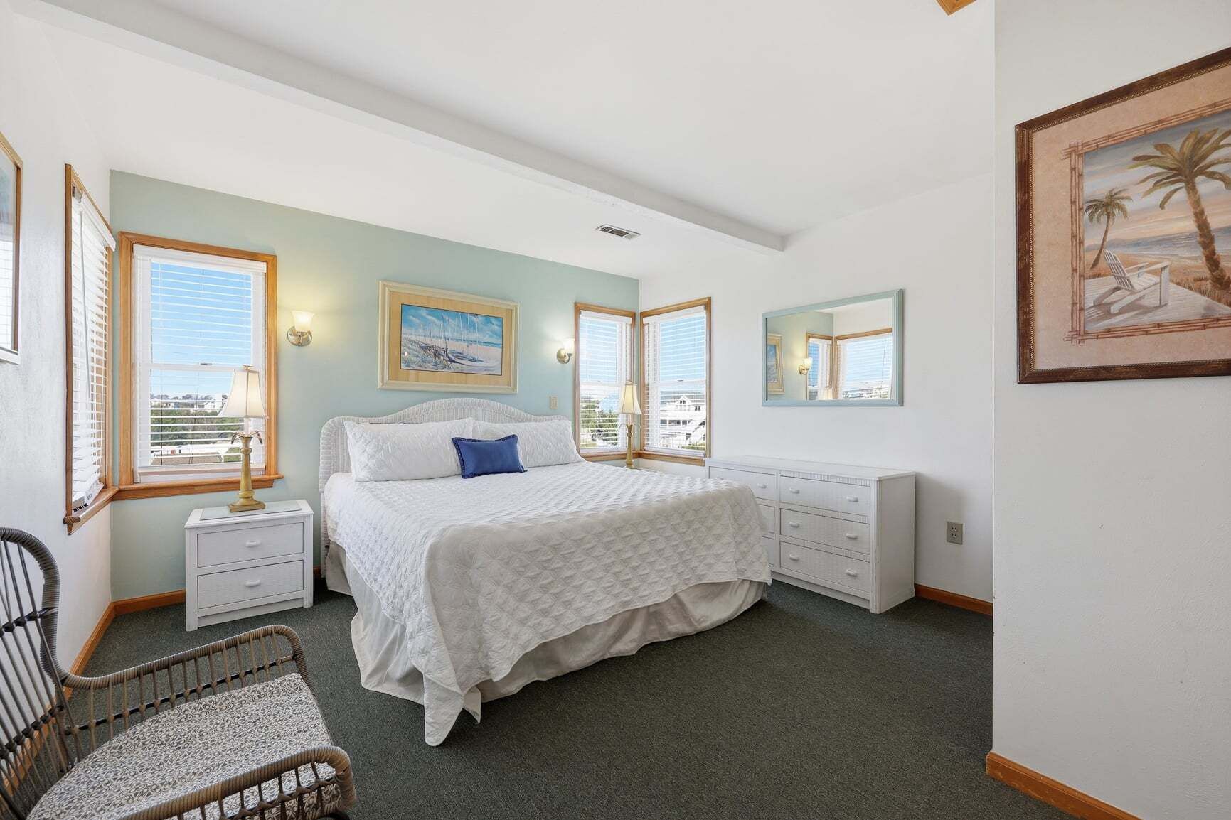 A bedroom with a bed, bedside tables, a chair, a dresser, and a painting.