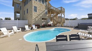 A two-story house with a swimming pool, deck chairs, and a barbecue area. - 1509 - Sandpiper - OBX Corolla Beach House w/ Pool & Hot Tub (Corolla)