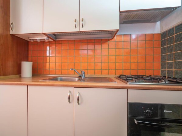 A kitchen with white cabinets, a sink, a stove, and a dishwasher.