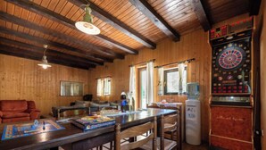 Una habitación acogedora con paredes de madera y un dardo. Hay una zona de bar con una mesa y sillas.