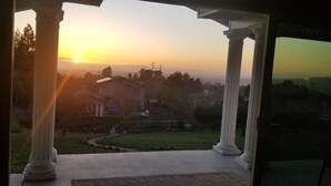 Vista da un portico coperto con colonne, affacciato su una zona residenziale al tramonto.