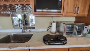 Una cucina con forno a microonde, tostapane e portabottiglie.
