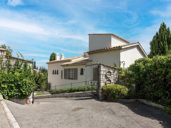 A two-story house with a stone facade, a tiled roof, and a gated driveway. - Mandelieu Villa with Rooftop (Mandelieu-la-Napoule)