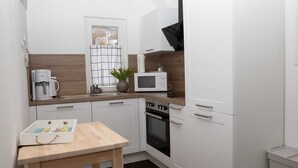 A compact kitchen with white cabinets, a microwave, a coffee maker, and a small table with a board game.