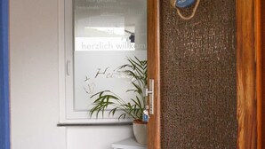 A wooden door with a life preserver decoration, a white door frame, and a potted plant on the wall. - Ferienwohnung West - Ferienwohnungen Heimathafen (Edertal)