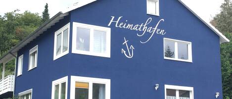 En blå byggnad med namnet ”Heimathafen” och en symbol som föreställer ett sjöankare.