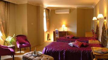A hotel room with a large bed, two chairs, a small table, and a lamp.
