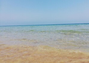 Une plage avec une eau claire et peu profonde et un rivage sablonneux.