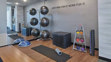 A gym with exercise equipment, a motivational wall quote, and a kettlebell rack.