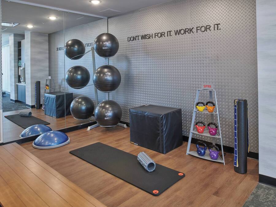 A gym with exercise equipment, a motivational wall quote, and a kettlebell rack.