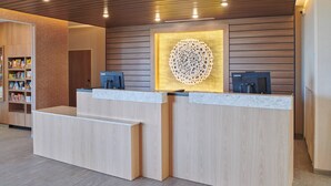 A reception desk with two computer stations, a wall-mounted decorative piece, and a snack shelf.
