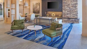 A modern living room with a stone fireplace, a flat-screen TV, and a blue patterned rug.