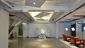 A modern lobby with a central sculptural installation, seating area, and a staircase. - Hotel 20 Alley (New Taipei City)