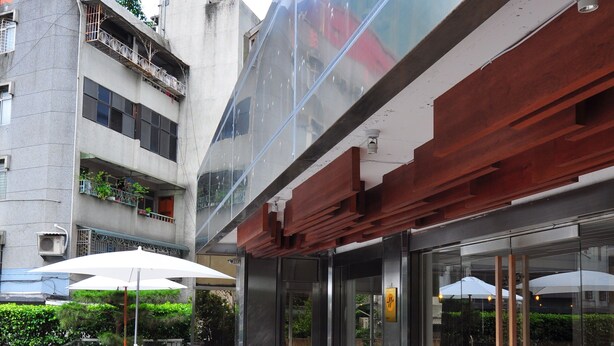 A modern outdoor area with a glass railing, wooden flooring, and outdoor seating. - Hotel 20 Alley (New Taipei City)