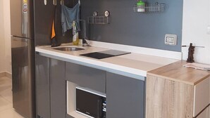 A modern kitchen with dark cabinets, stainless steel appliances, and a wooden countertop. - Arcadia beach condo by Jiabo (Pattaya)