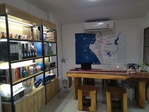 A room with a wooden desk, two stools, a bookshelf, and a map on the wall.