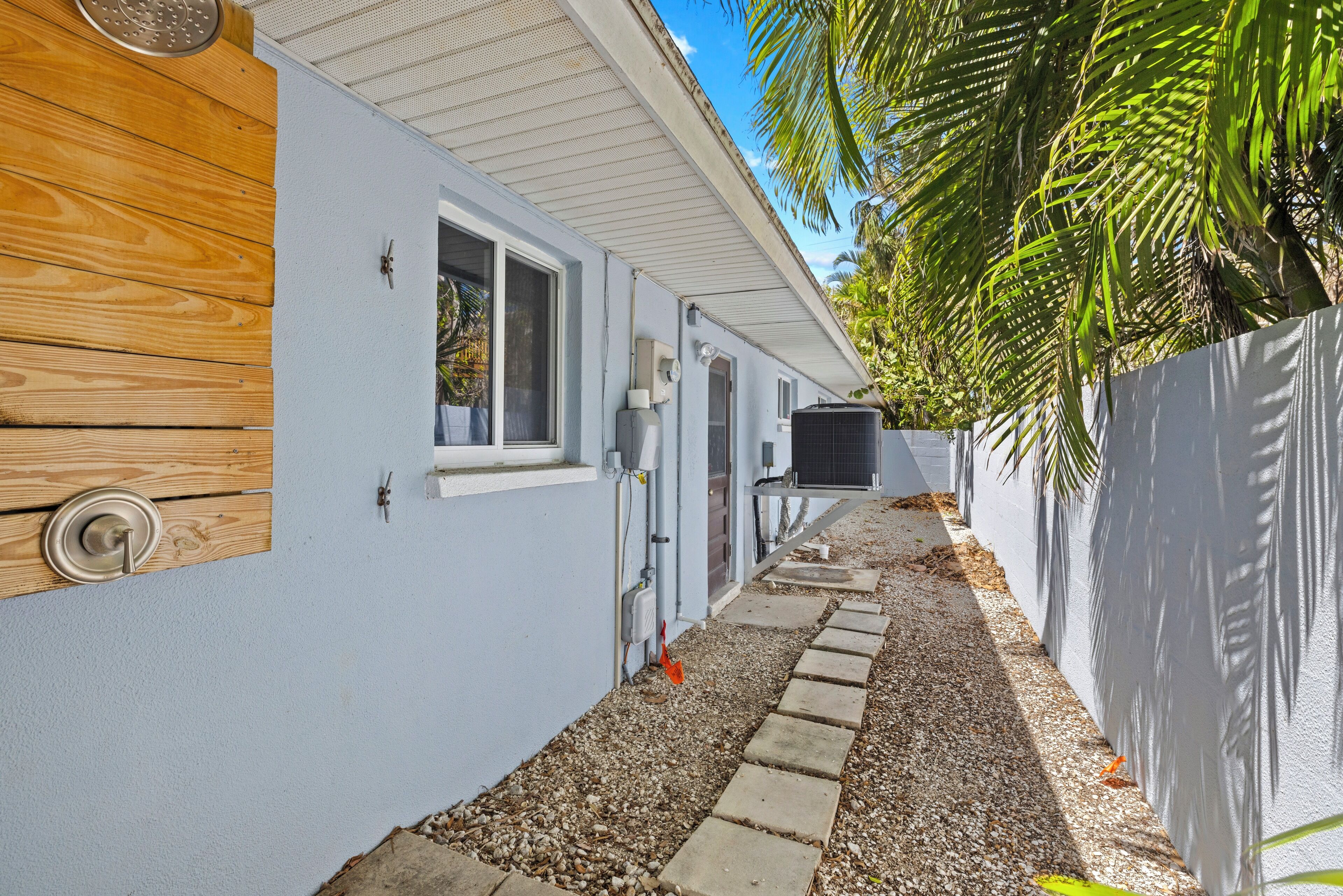 A narrow pathway leading to a house with a wooden door and a window.