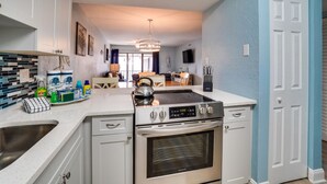 A modern kitchen with white cabinetry, a stainless steel stove, and a black oven.