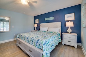 A bedroom with a bed, nightstands, a ceiling fan, and a window with blinds. - Sea Life at Runaway Bay 211 (Bradenton Beach)
