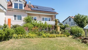 Une maison d’habitation dotée d’un toit équipé de panneaux solaires, d’un balcon et d’un jardin bien entretenu.