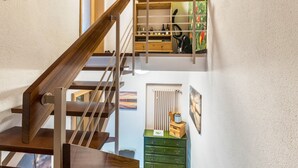 Un escalier en bois avec une rampe en métal, une commode verte et un radiateur.