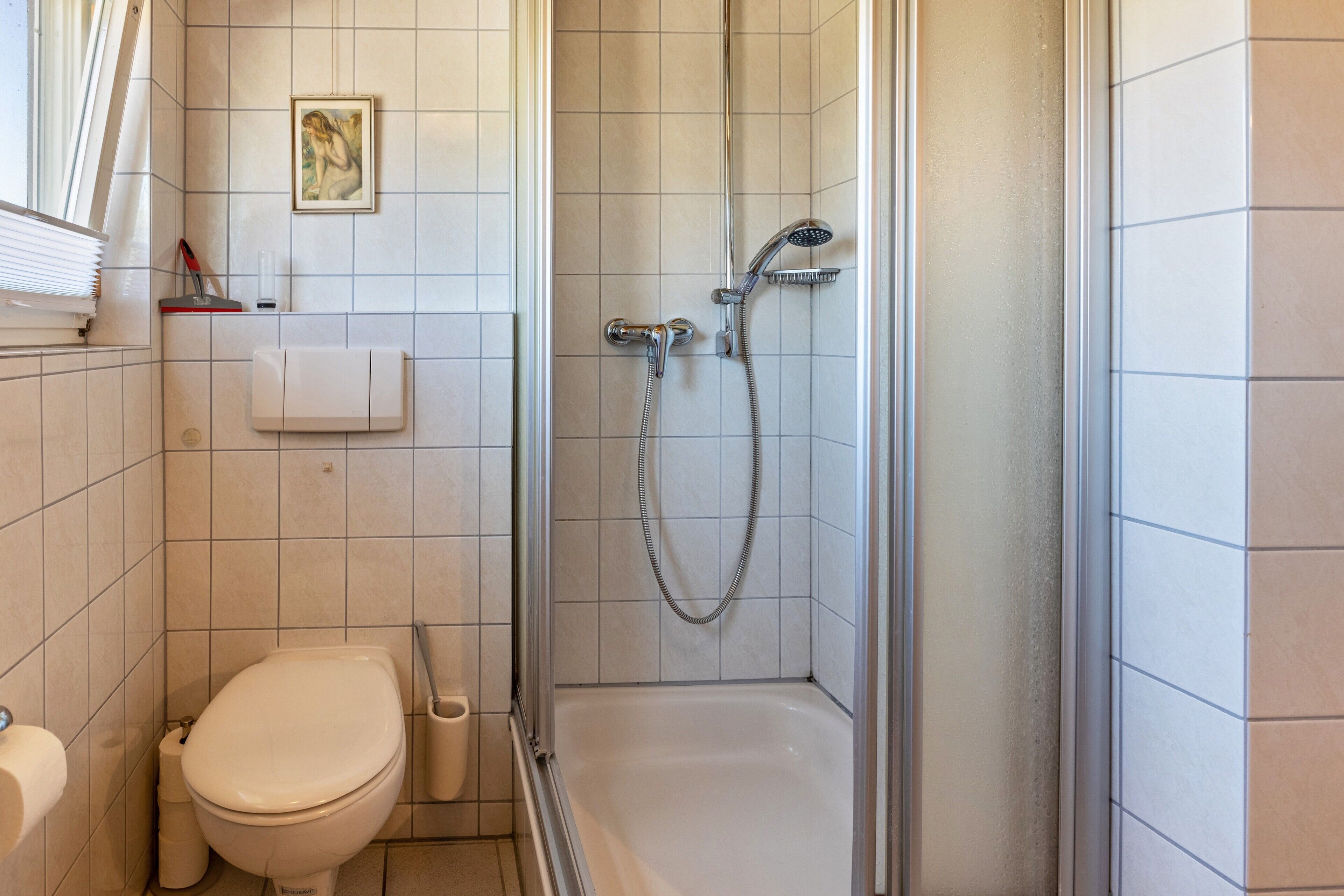 A bathroom with a toilet, a shower, and a sink.