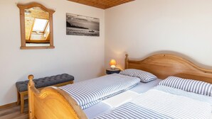 A room with a wooden bed, a bench, a nightstand with a lamp, a skylight, and a framed picture on the wall. - Cozy Holiday Apartment "Sonnenuntergang" on Lake Constance with Lake View & Wi-Fi (Gaienhofen)
