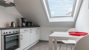 Een moderne keuken met dakraam, witte kastjes, een fornuis en een eettafel met een rode kom.