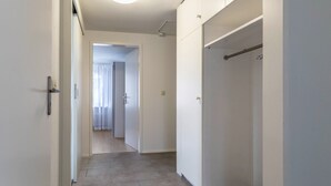 Een hal met een deur naar een kamer, een kapstok en een betegelde vloer.