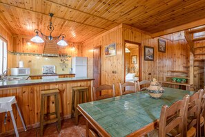 A wooden interior with a kitchen area, dining table, and chairs.